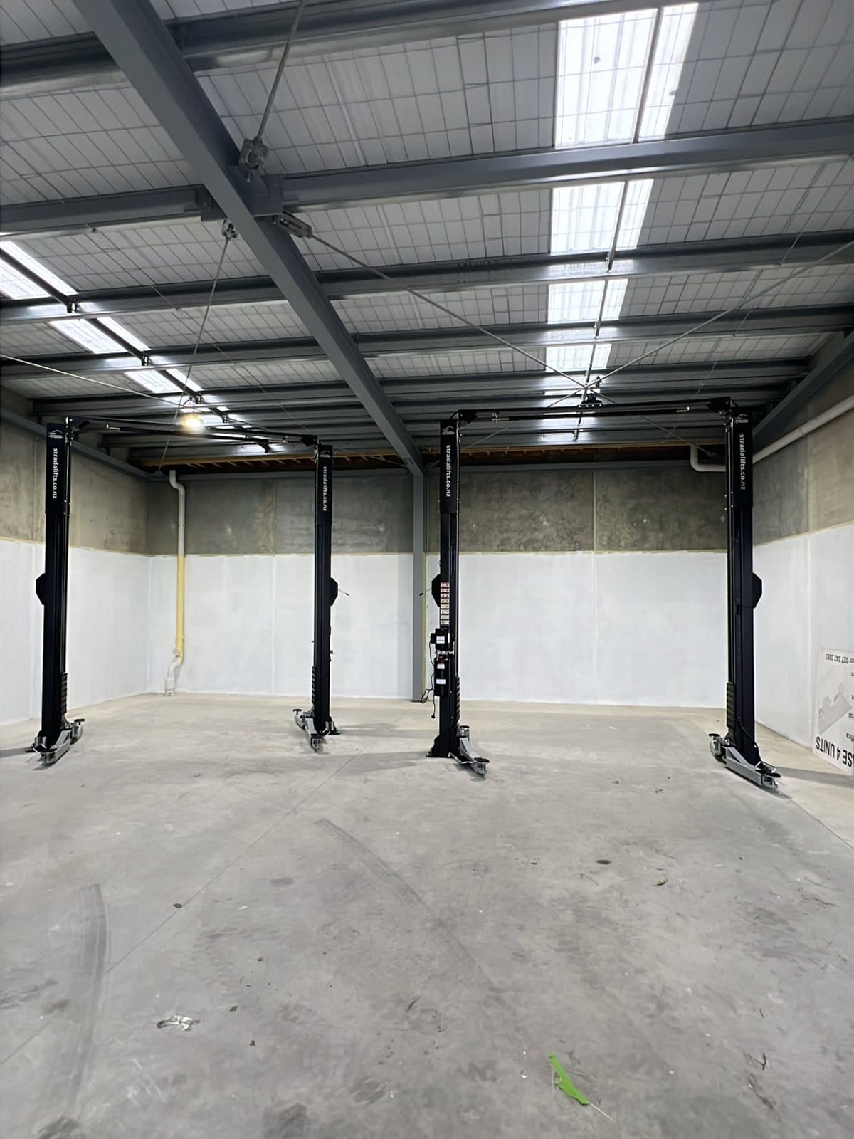 Four black two-post hoists installed across a new four-bay workshop