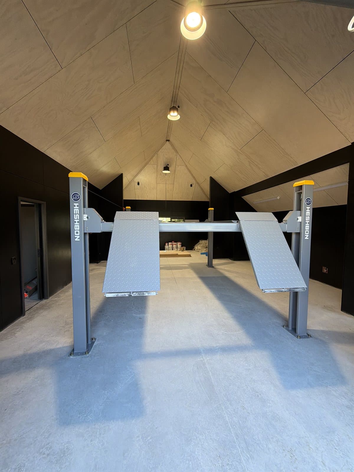 Grey Heshbon four-post parking lift installed in a timber-lined private garage