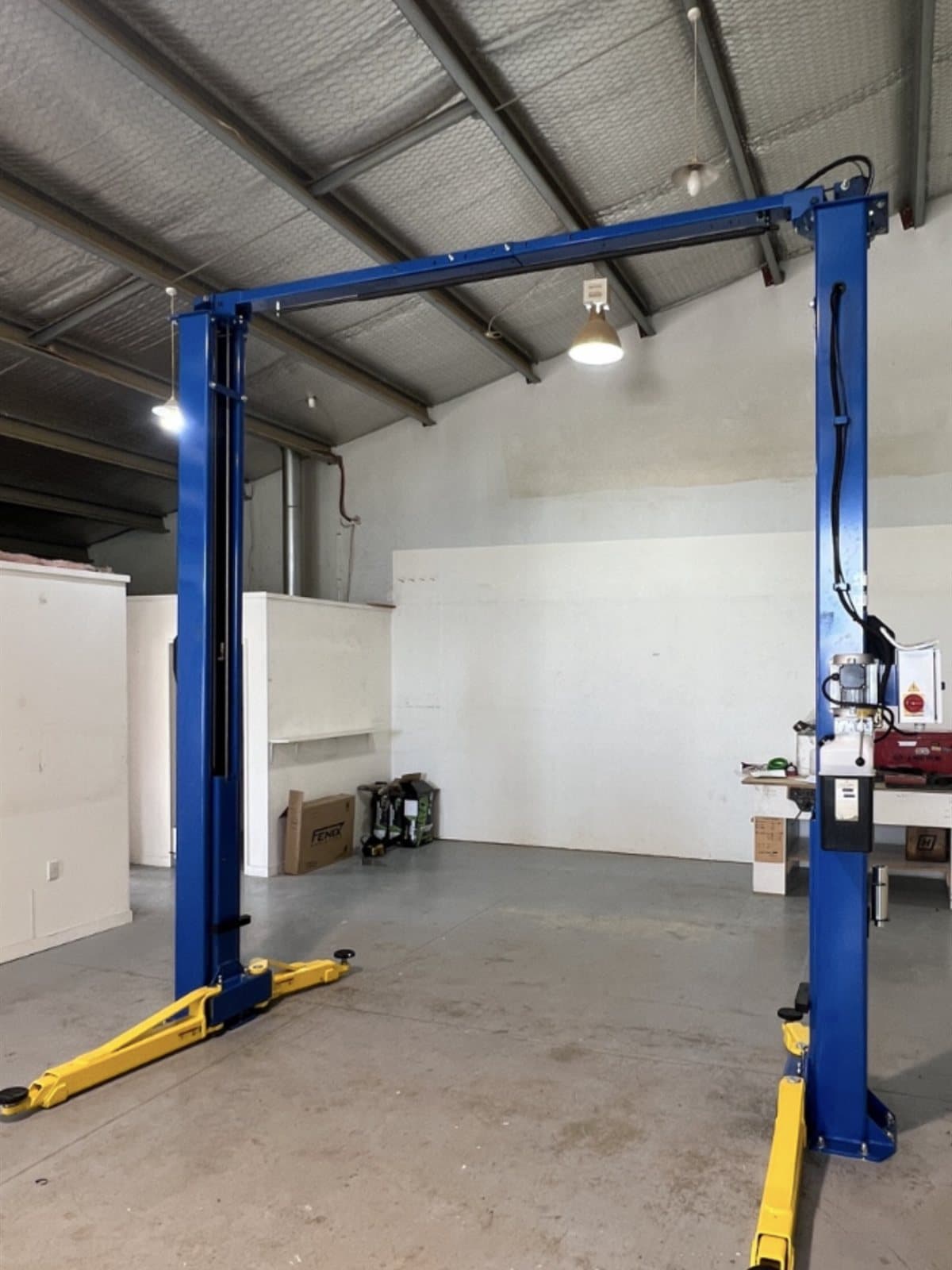 Blue two-post hoist installed in a clean new workshop bay