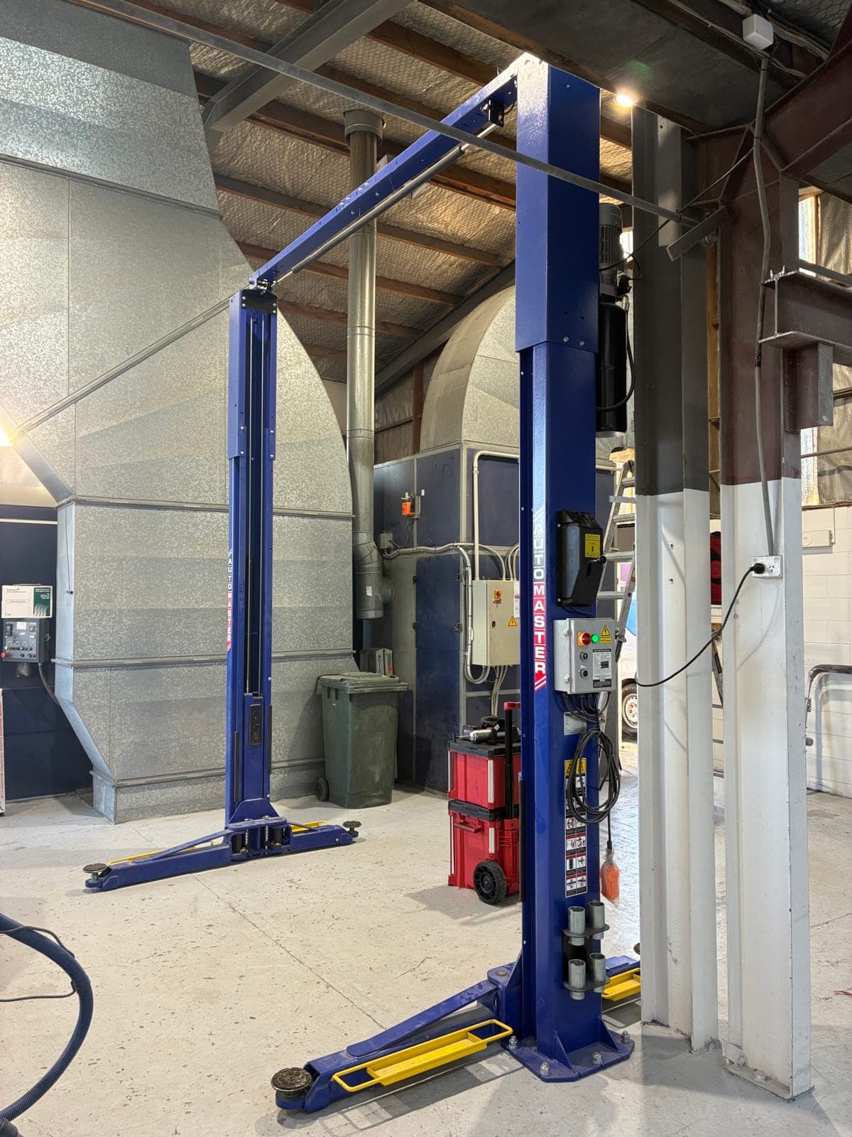 Blue two-post hoist installed in an industrial workshop