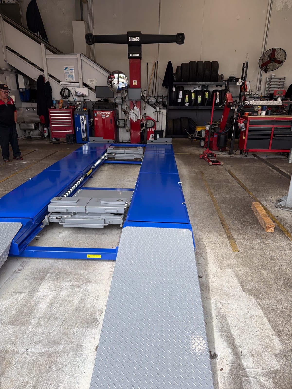 Blue alignment lift with run-up ramps installed in a busy workshop